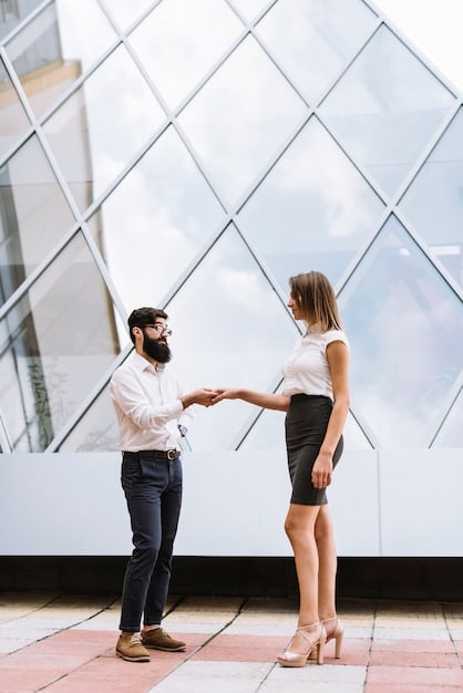 Two businesspeople shaking hands in front of a skyscraper, symbolizing a successful strategic partnership.