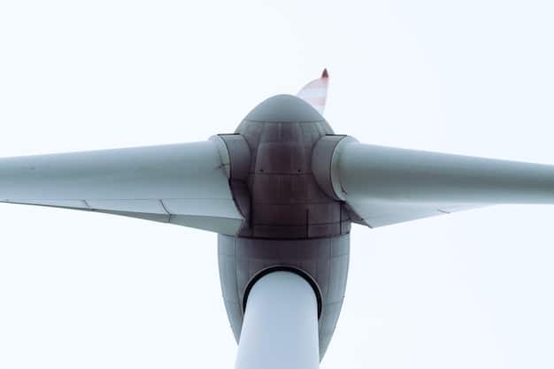 A detailed close-up of a wind turbine rotor against a bright, clear sky, showcasing the sleek design and aerodynamic efficiency of modern wind power technology.