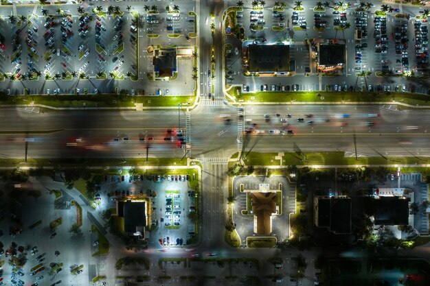 A top-down view of a modern city intersection with translucent data overlays showing communication lines between smart traffic lights and multiple autonomous vehicles, illustrating V2X connectivity.