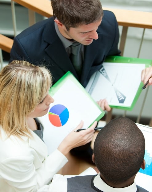A corporate board room with diverse executives discussing a sustainability report, with charts and graphs on a large screen displaying environmental metrics and compliance targets. The room looks modern and professional.