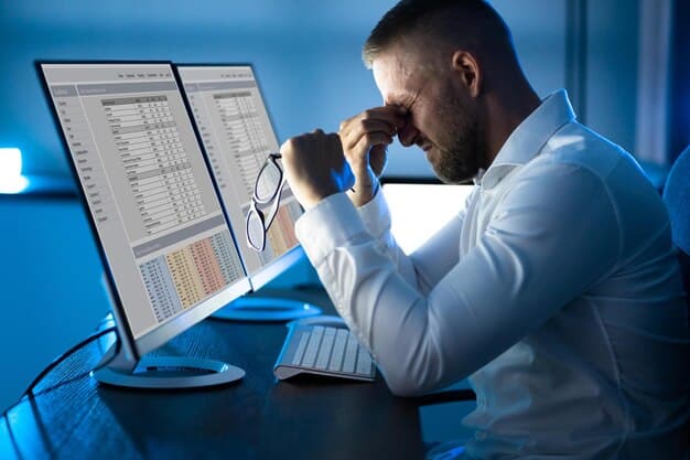 A person looking stressed while reviewing financial documents, with charts and graphs on a computer screen in the background, symbolizing financial burden from healthcare costs.