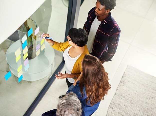 A diverse group of designers collaborating around a large interactive holographic display, sketching user flows in mid-air, symbolizing the collaborative and extended reality aspects of modern UX.