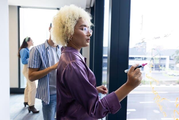 A diverse group of entrepreneurs in a modern co-working space, collaboratively brainstorming and sketching out business strategies on a glass wall, surrounded by digital graphs and charts.