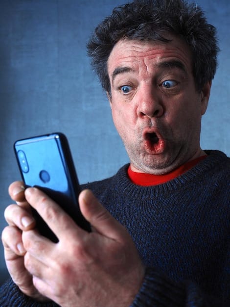 A person looking at a phone with a skeptical expression, with deepfake detection software running in the background. The software highlights areas of manipulation on the phone's screen. This image symbolizes the active and cautious approach needed in The Rise of Deepfakes: How to Spot Them and Protect Yourself from Misinformation.