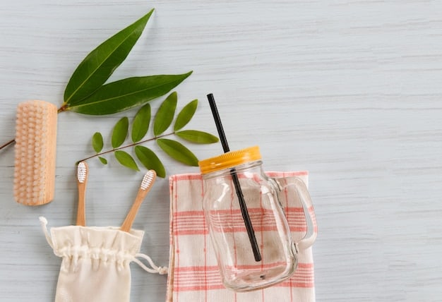 A neat arrangement of sustainable alternatives on a wooden table, including a stainless steel water bottle, a bamboo toothbrush, reusable shopping bags, and glass food containers, all brightly lit.
