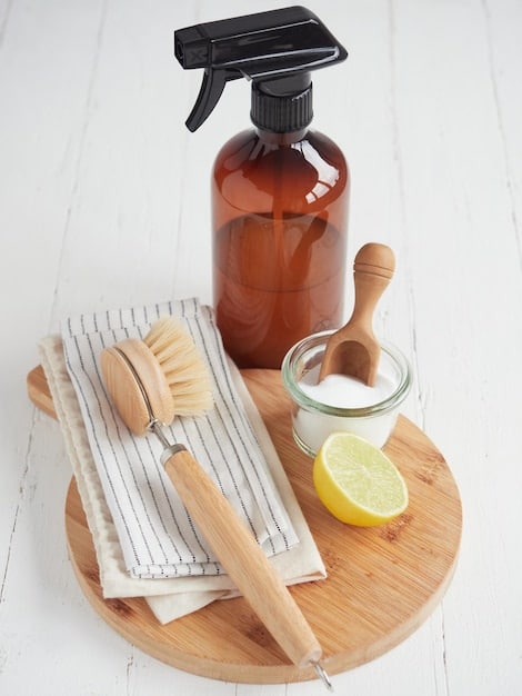 A neat arrangement of cleaning tools: a reusable spray bottle filled with a clear liquid, a scrubbing brush with natural fibers, and a stack of bamboo cloths.