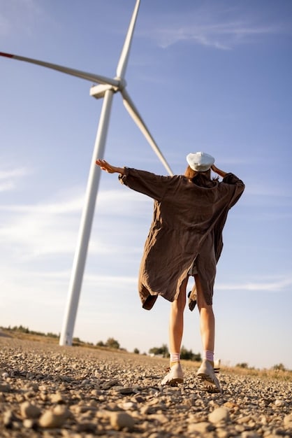 A close-up shot of workers installing wind turbine blades on a wind farm. Visibility conditions are partly cloudy. Some are inside the turbine while others are on the ground, looking at the turbine. The image emphasizes the hands-on labor and skills needed in the wind energy sector, vital for understanding